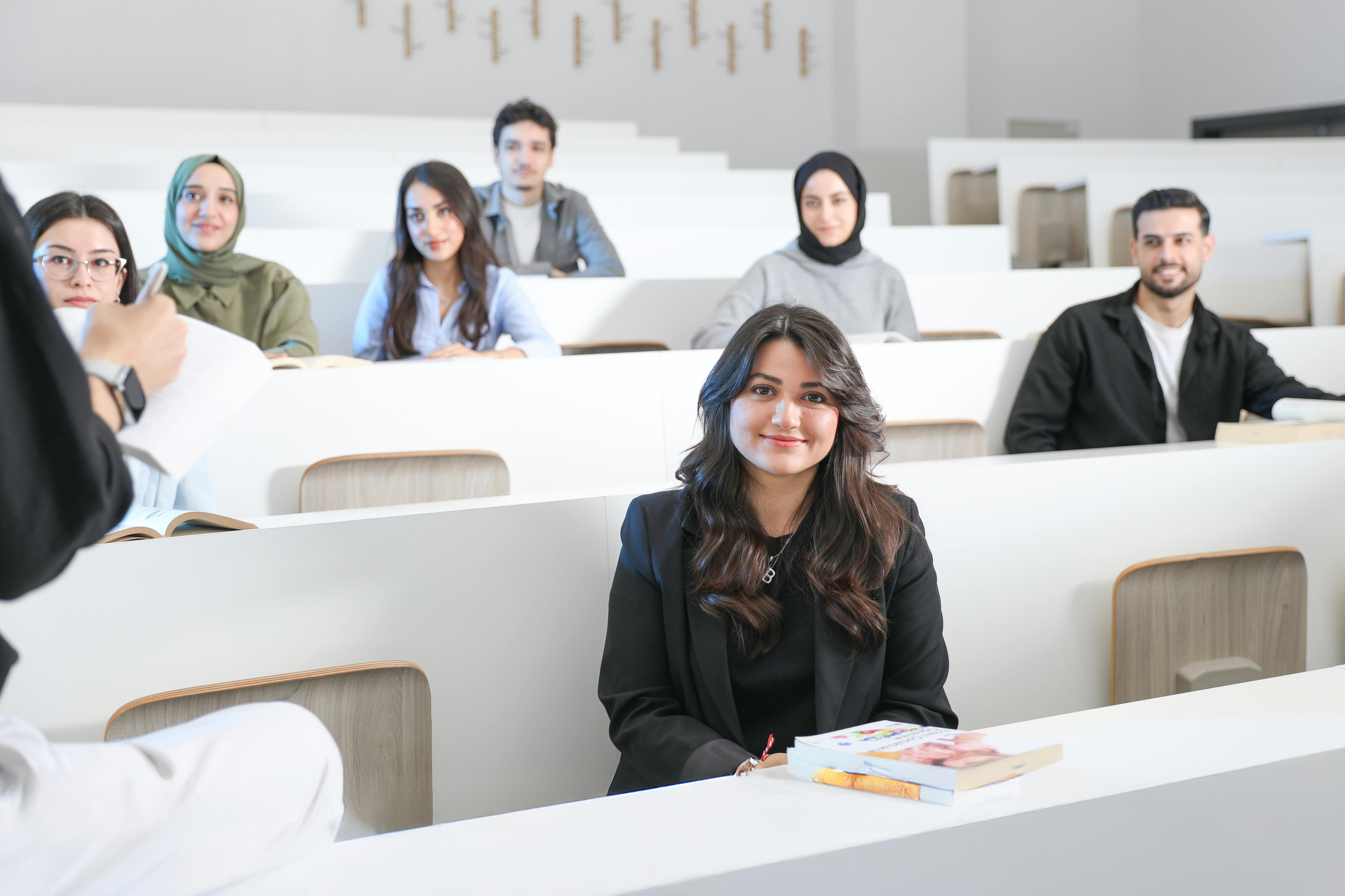 COURSES Students listening attentively in a bright university lecture hall.
